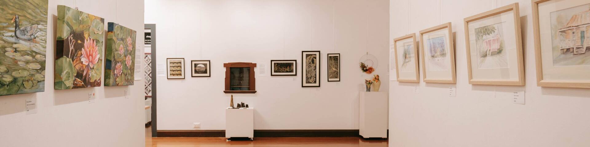 An art gallery with wooden floors and white walls.