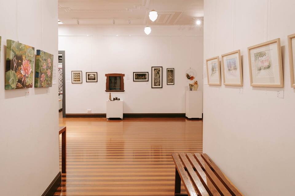 An art gallery with wooden floors and white walls.