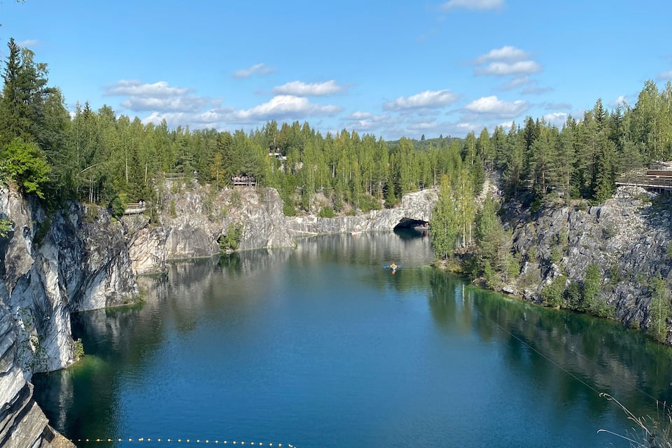 Un lago transparente rodeado de riscos rocosos y un bosque denso.