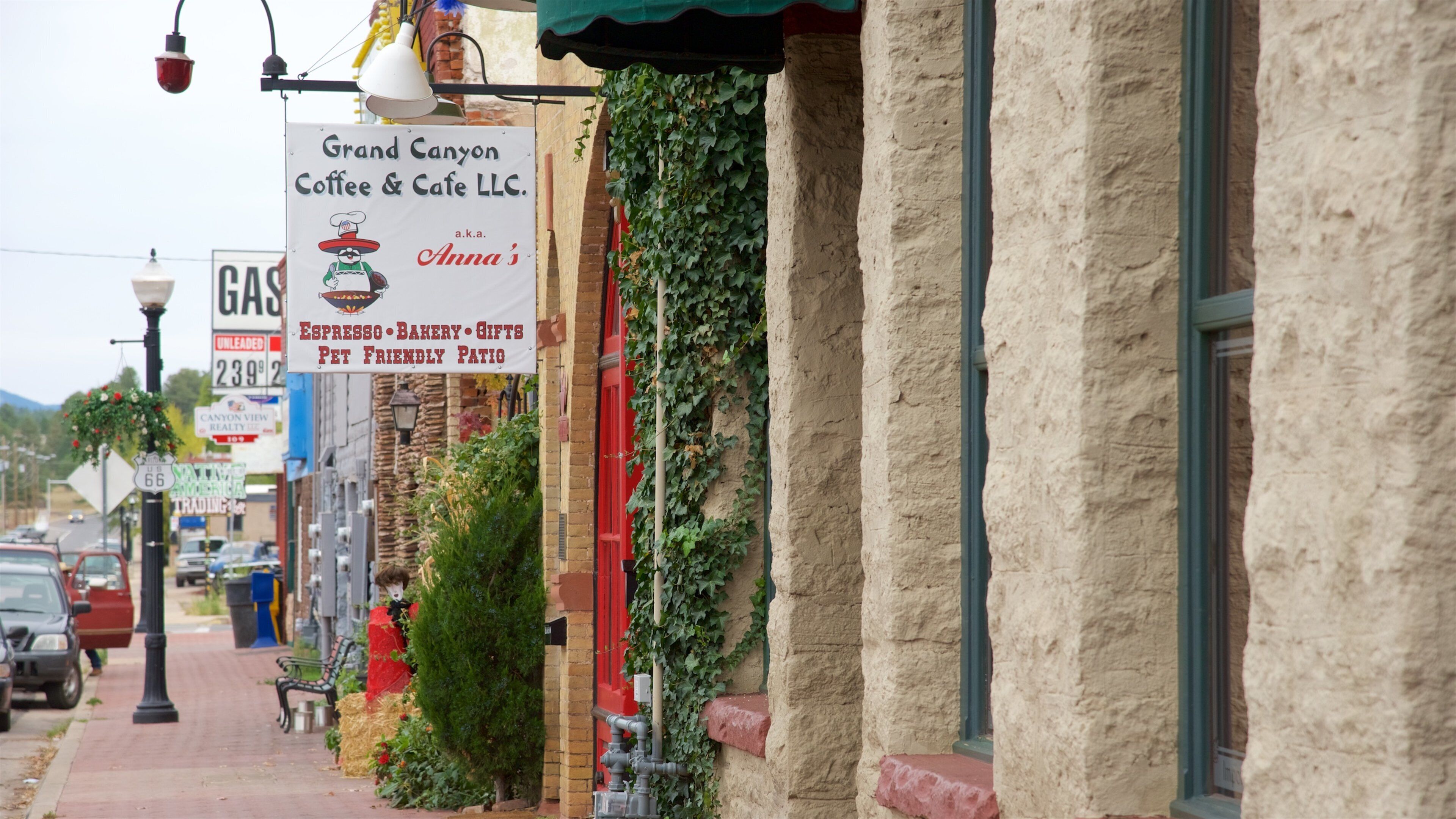 A street with a coffee shop named Grand Canyon Coffee & Cafe LLC, a gas station, and a red building with ivy.