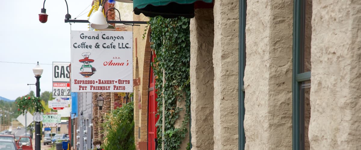 A street with a coffee shop named Grand Canyon Coffee & Cafe LLC, a gas station, and a red building with ivy.