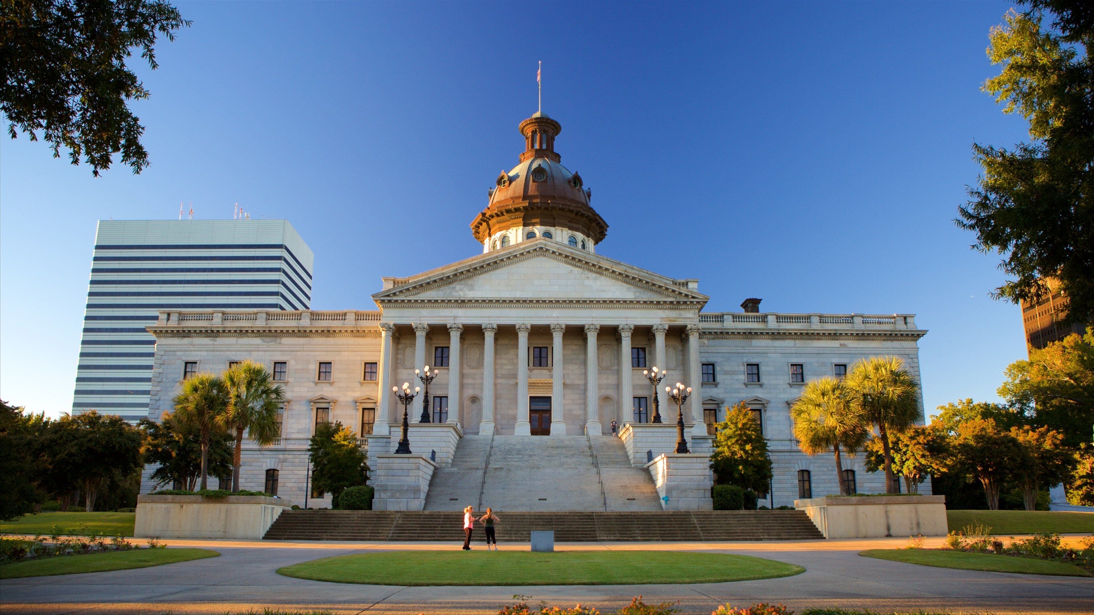 A large neoclassical building with a prominent dome and columns, surrounded by well-maintained lawns and trees.