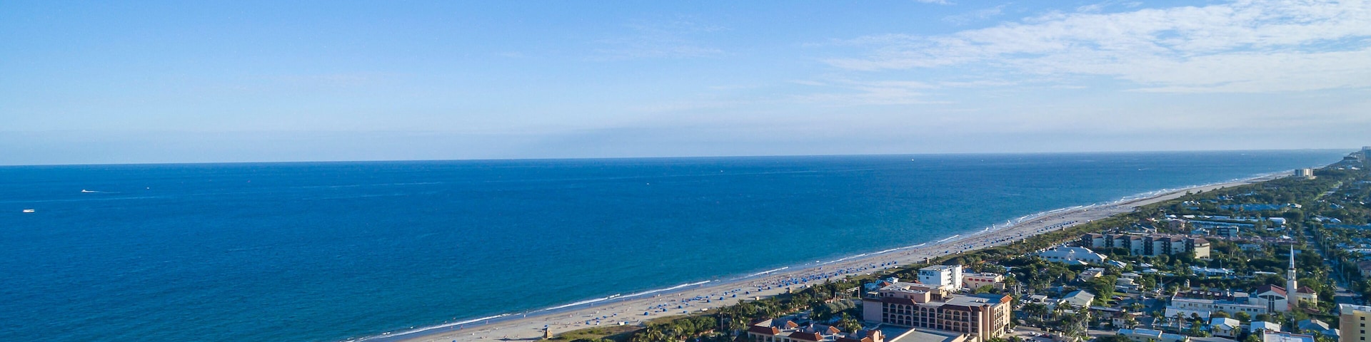 Un paisaje urbano costero con playa, edificios y un cielo azul despejado.