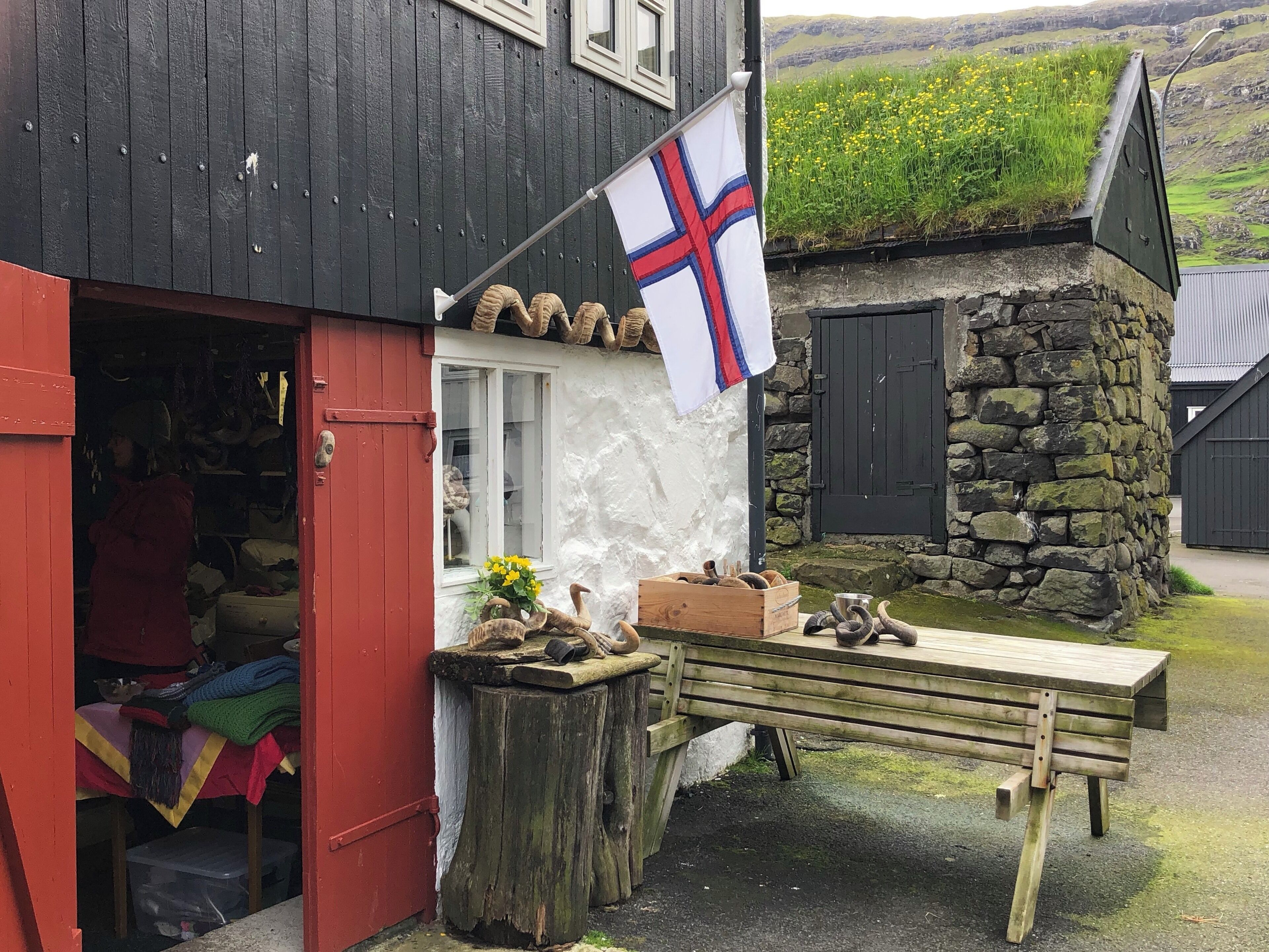 A traditional building with a flag, a wooden bench, and a stone wall.