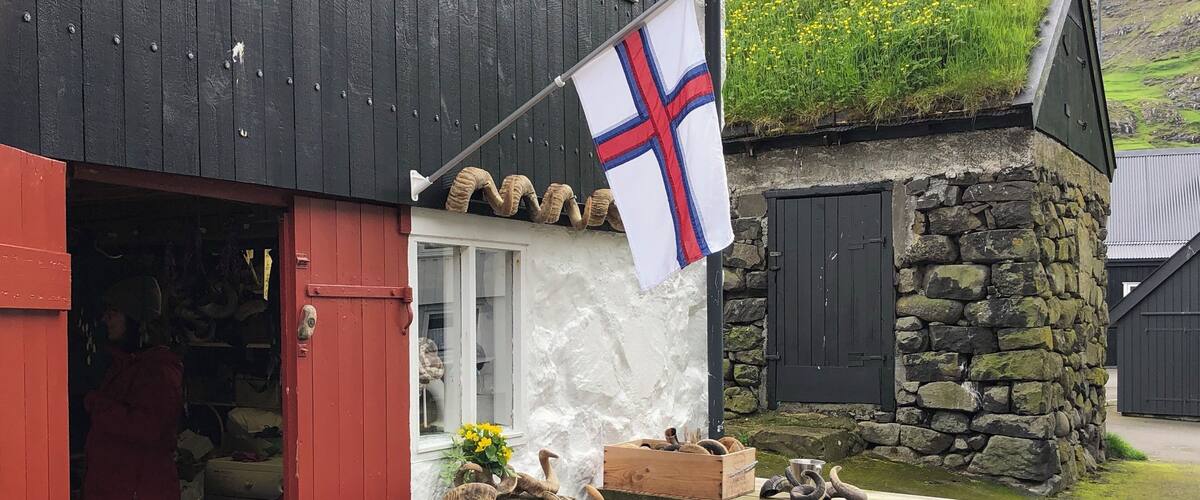 A traditional building with a flag, a wooden bench, and a stone wall.