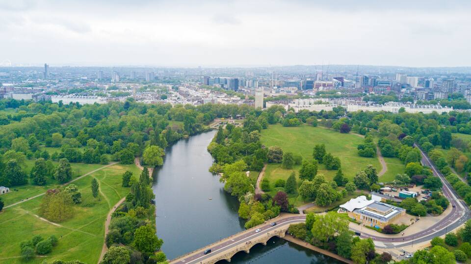 A river flowing through a city with a bridge and surrounding greenery.