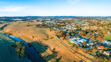 A river winding through rolling hills, a small town with houses and buildings, and distant mountains.