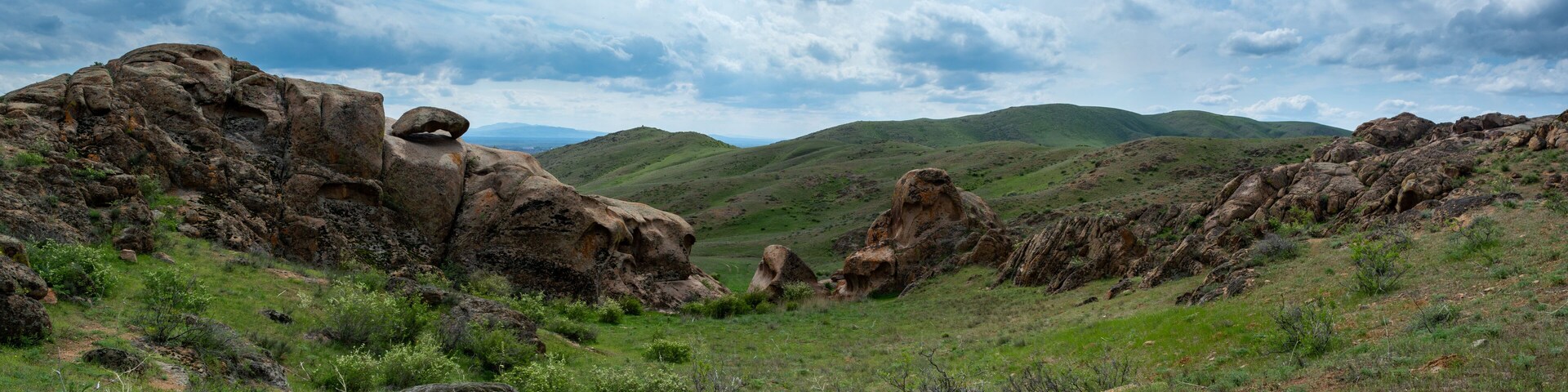 Red stone rocks and hills with bizarre shapes. Panoramic image. Spring. Almaty region, Kazakhstan.