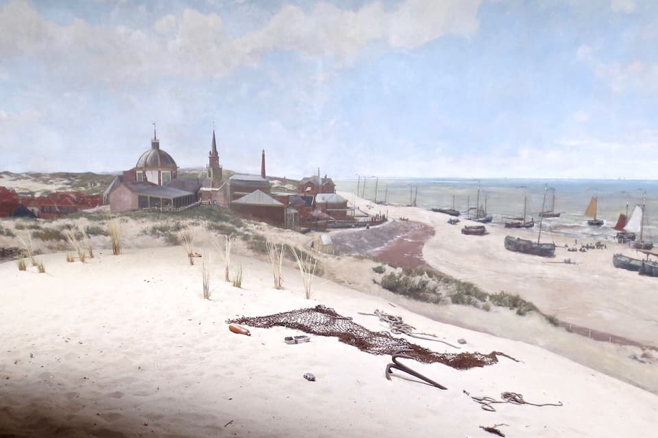 Een kustplaats met een opvallende kerk, zandduinen en een haven met boten.