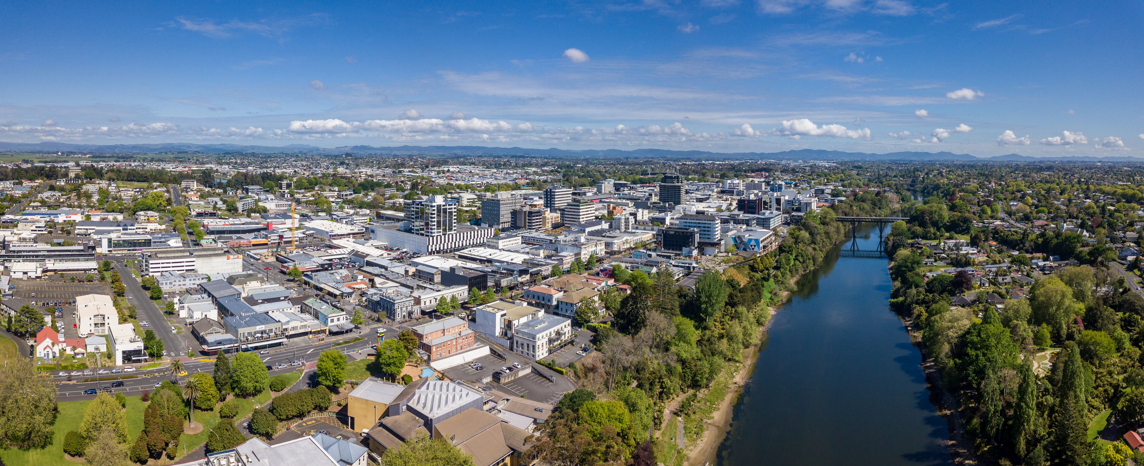 A cityscape with a river, bridges, and distant mountains.