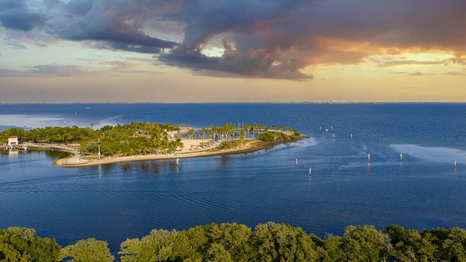 A tropical island with a beach, palm trees, and a lighthouse.