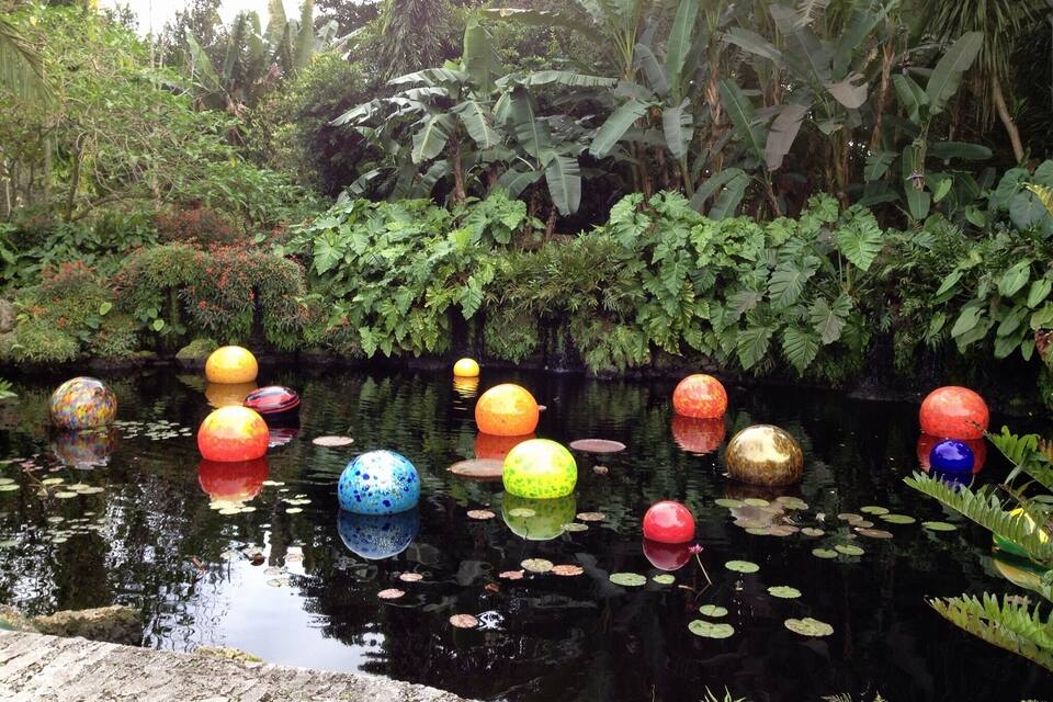A pond with colorful floating spheres and lush greenery.