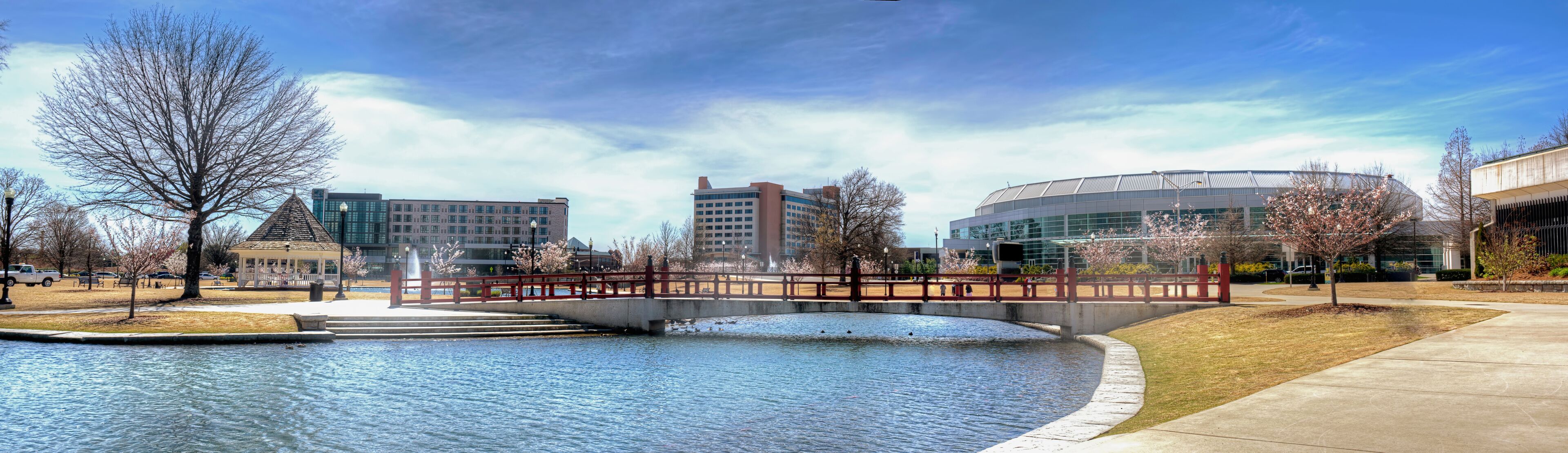 A bridge over a water feature with modern buildings in the background.