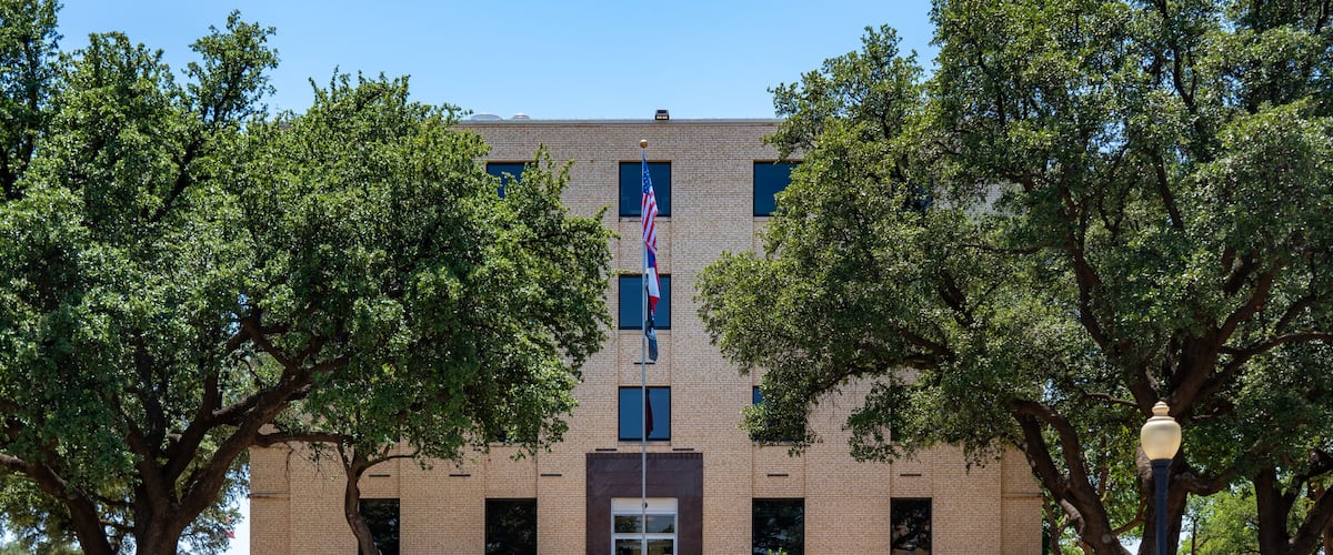 A brick building with a flag, trees, and a sign for Howard Veterans County Memorial.
