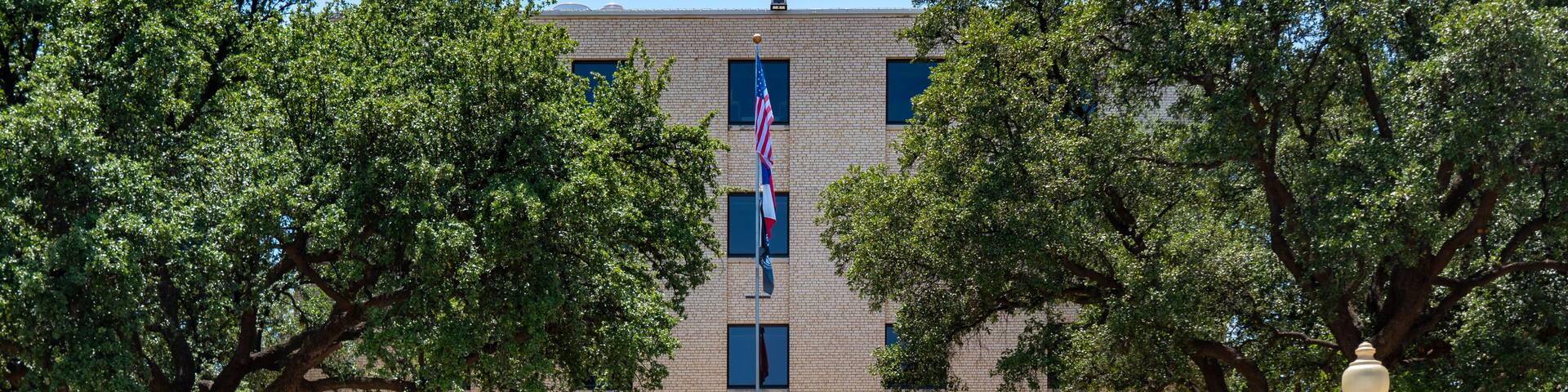 A brick building with a flag, trees, and a sign for Howard Veterans County Memorial.
