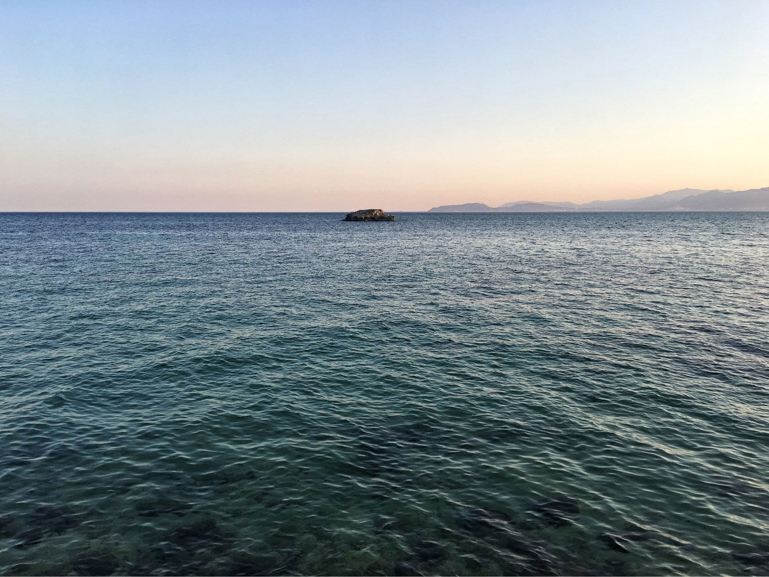 A calm sea with a small island in the distance.
