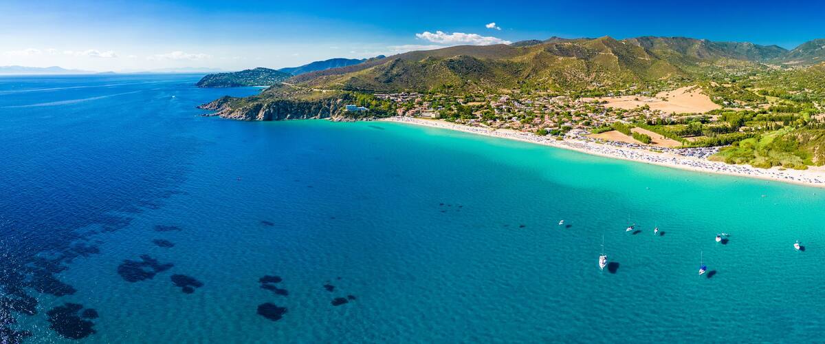 Eine Küstenstadt mit Strand, Booten und Bergen.
