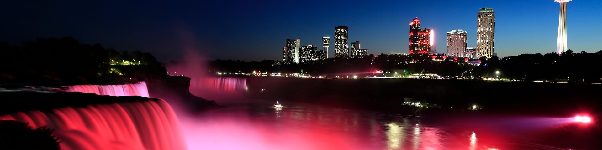 Niagara Falls at dusk including the skyline of the Canadian city of the background