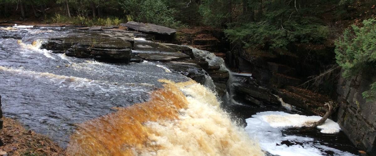 A waterfall cascading over rocks in a forested area.