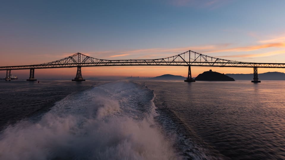 A suspension bridge over a body of water with waves in the foreground.