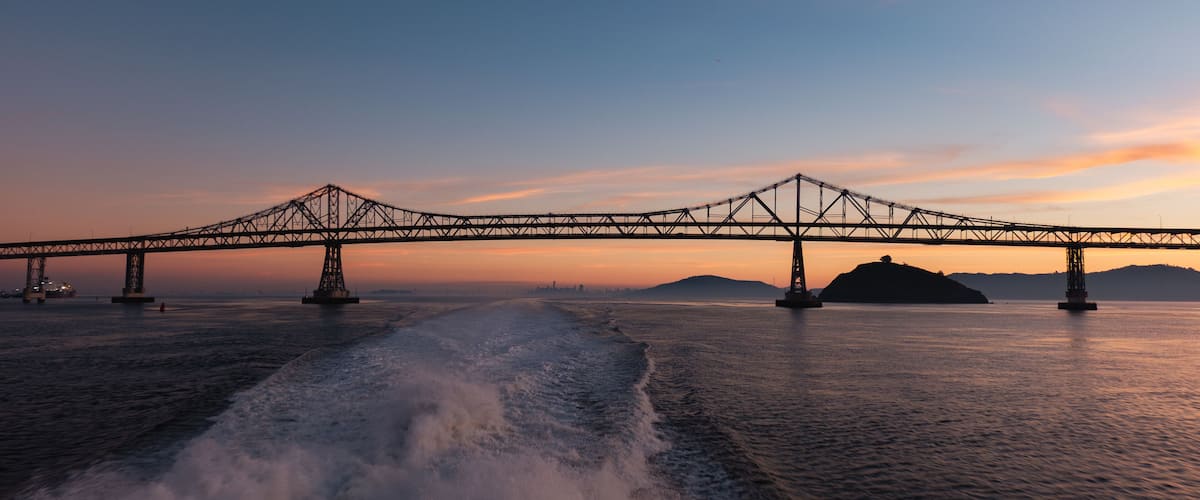 A suspension bridge over a body of water with waves in the foreground.