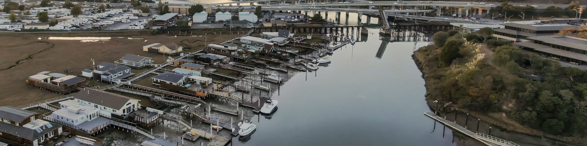 Aerial view of Corte madera Creek in Larkspur, Greenbrae, California, USA, at sunrise. Houses line the riverbank with docks and boats with Mount Tamalpais in the background.