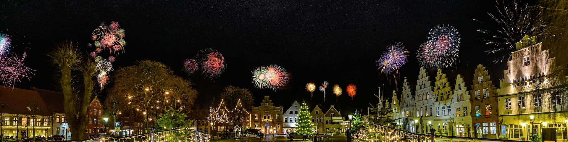 Charming town bathed in festive lighting and fireworks, creating a romantic atmosphere for New Year's Eve with the spectacular display of colors and lights. Friedrichstadt at night during the New Year