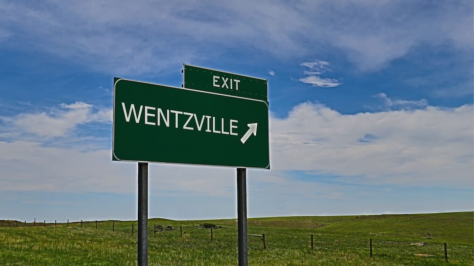 A green road sign indicating an exit for Wentzville.