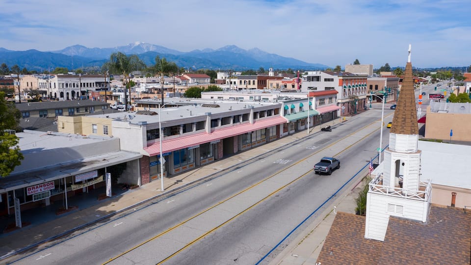 A street with buildings, a mountain range, and a church steeple.