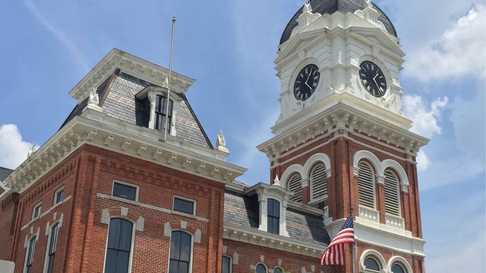 A historic building with a clock tower and an American flag.