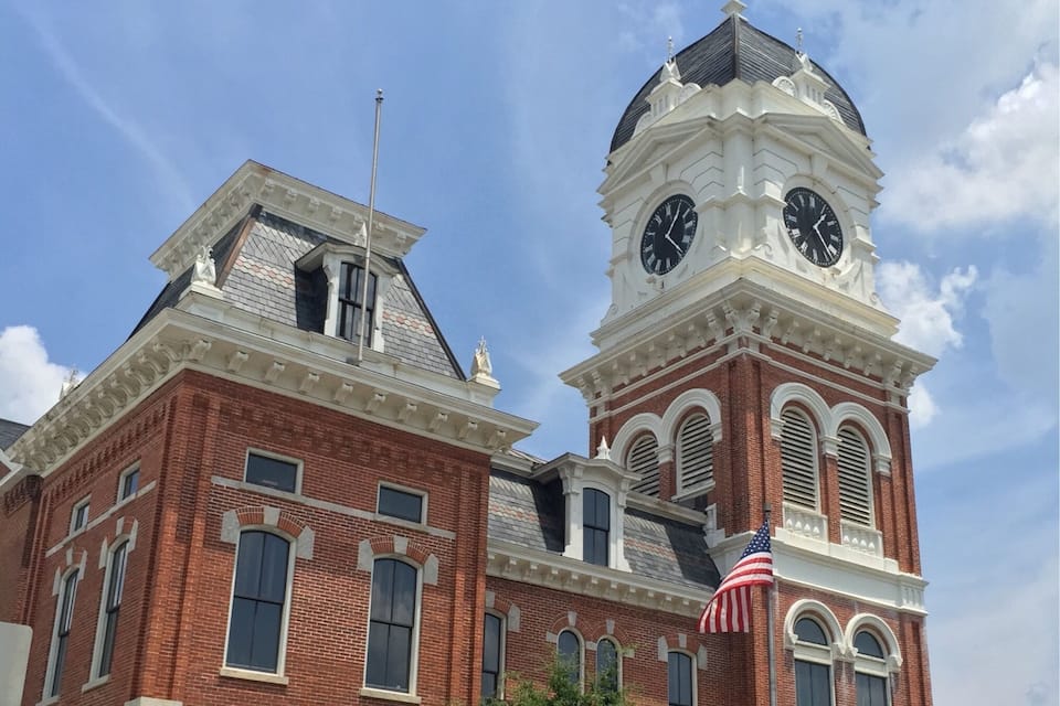 Um edifício histórico com uma torre de relógio e uma bandeira americana.