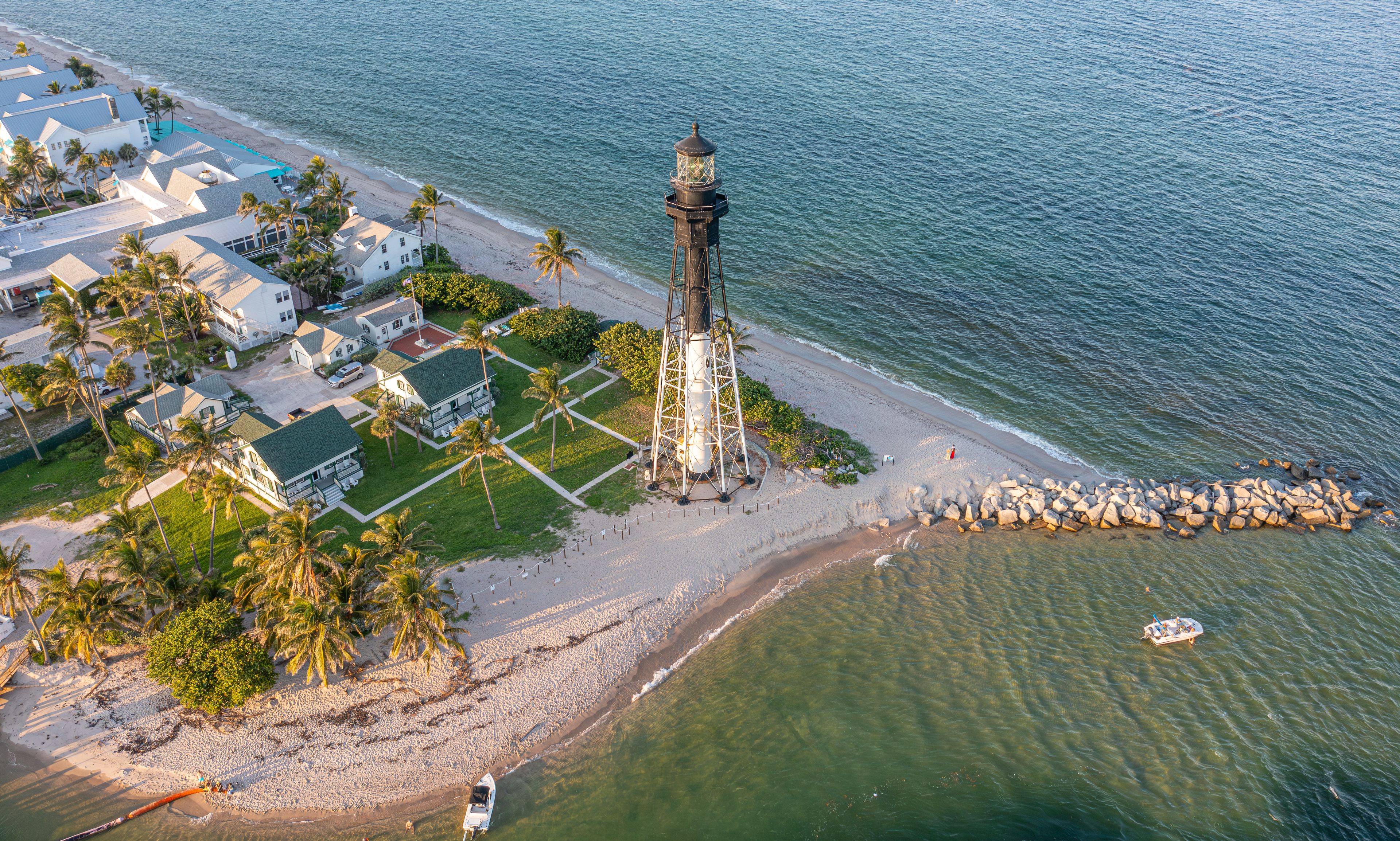 Zona costera con un faro, playa y edificios residenciales.