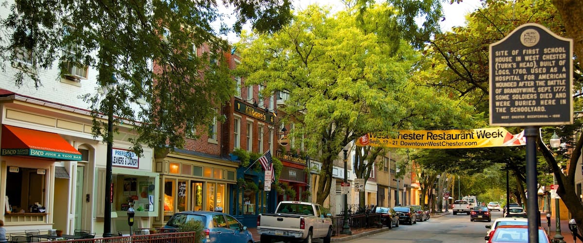 A street lined with historic buildings, a sign for Kildogge's Pub, and a banner for West Chester Restaurant Week.