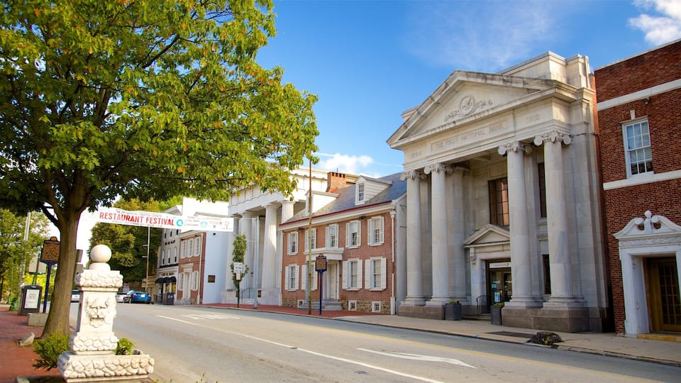 A street with historic buildings, including a bank with columns and a sign for the Restaurant County Festival.