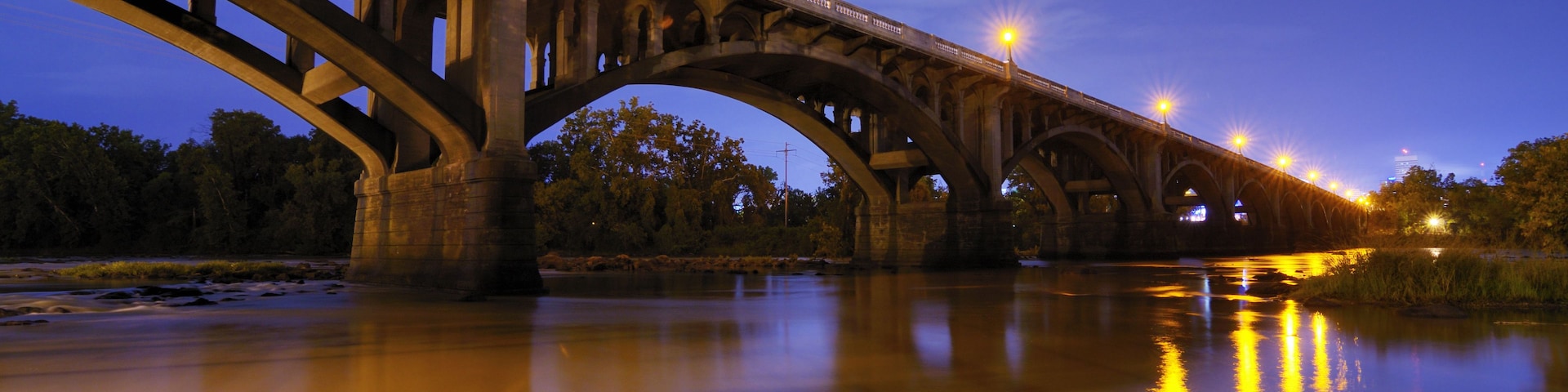 Eine Brücke mit mehreren Bögen über einem Fluss im Abenddämmerung.