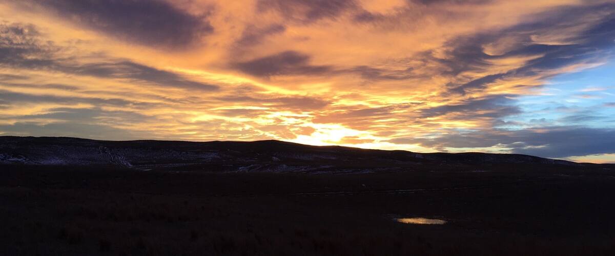 A sunset over a mountainous landscape with a small lake.