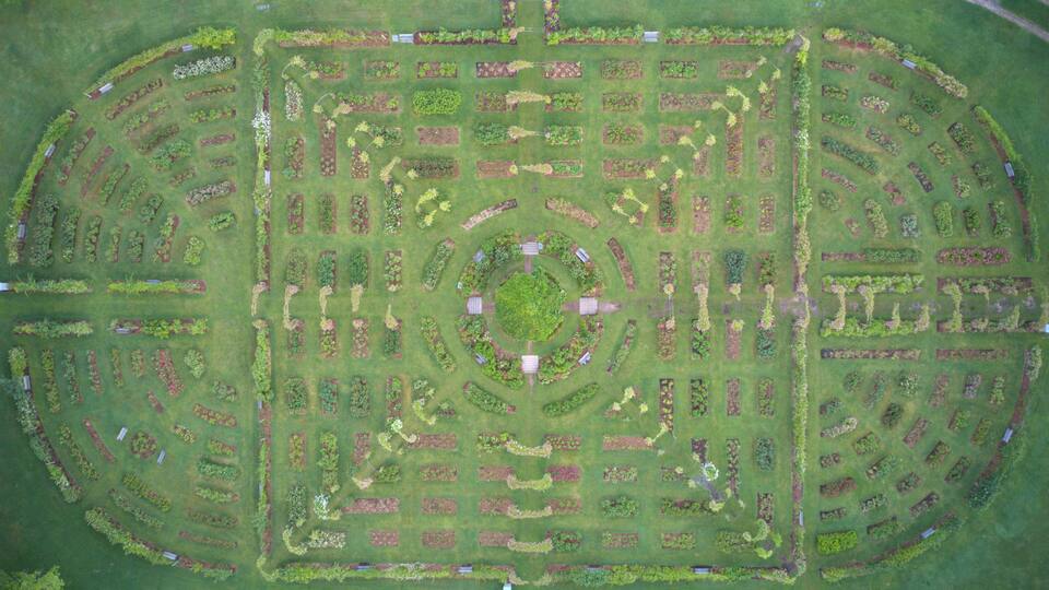 An aerial view of a meticulously landscaped garden with geometric patterns and a central circular area.