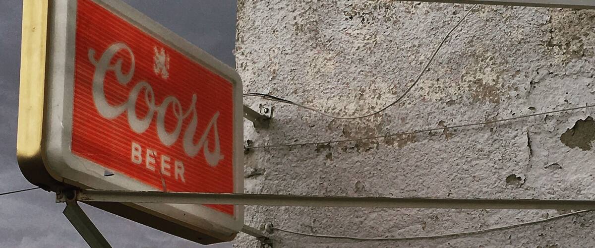 A sign for a 'Lost Bar' from 1936 and a 'Cokes Beer' sign.