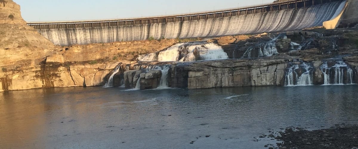 A dam with multiple waterfalls and a river below.