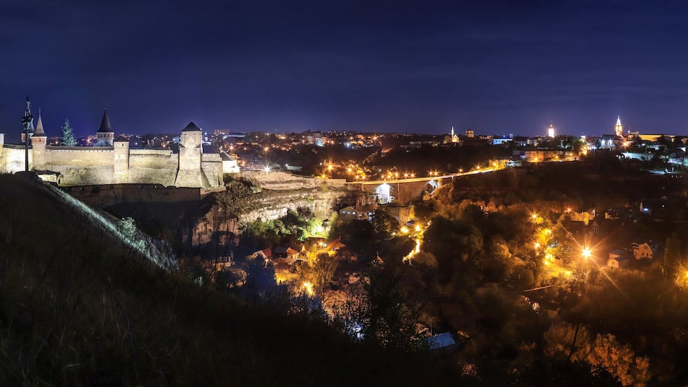Panoramic night view of ancient fortress castle in Kamianets-Podilskyi, Khmelnytskyi Region, Ukraine. Old ?astle photo on a postcard or cover. Long exposive