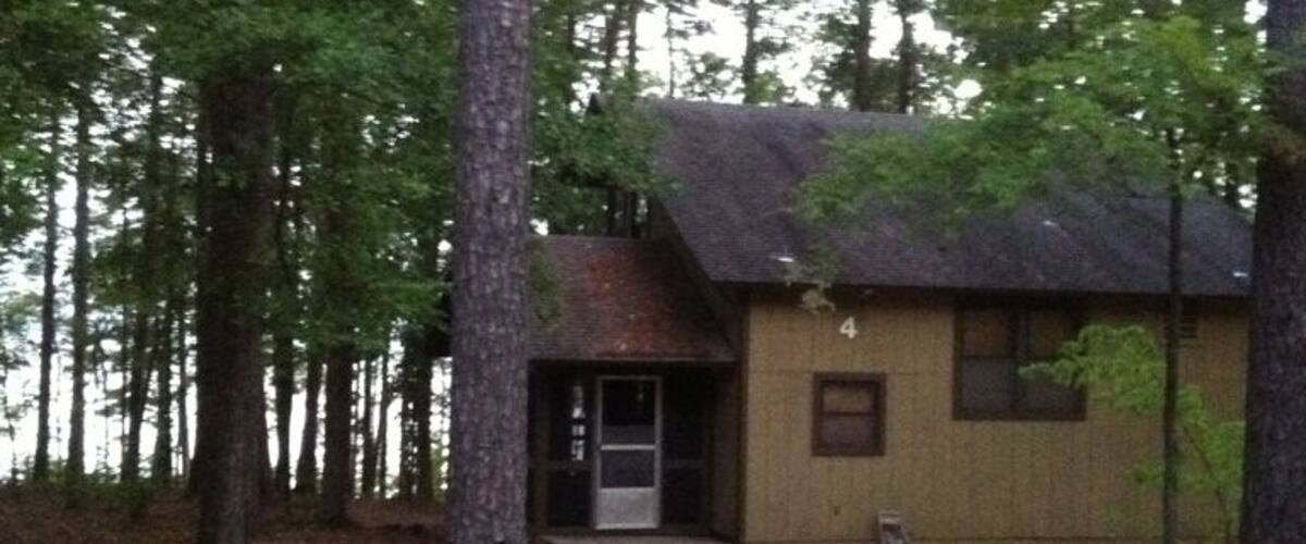 A small cabin surrounded by tall trees in a forest.