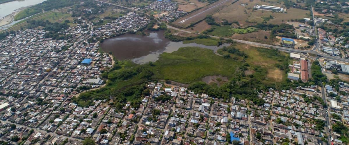 An aerial view of a city with a river, a bridge, and a large green park.