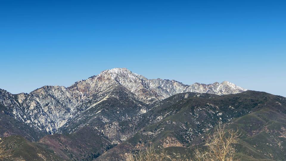 A mountain range with snow-capped peaks and a clear blue sky.