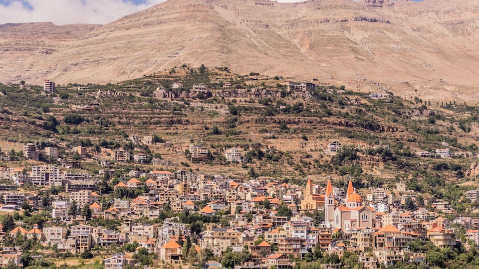 A town nestled in a valley with a prominent church and a mountain in the background.