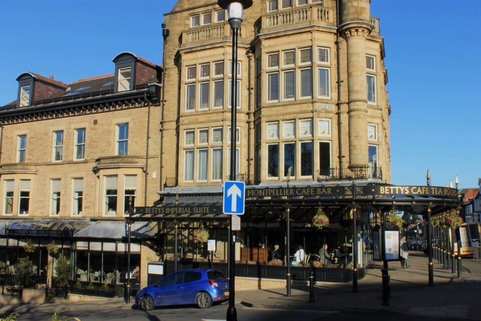 A historic building with a blue car parked in front, a sign for 'Bettys Imperial Suite', and a 'Montpellier Cafe Bar'.