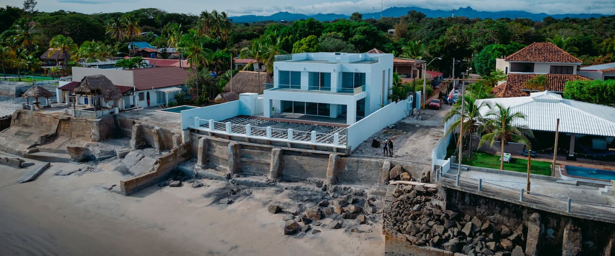 A coastal town with a prominent white building, sandy beach, and lush greenery.