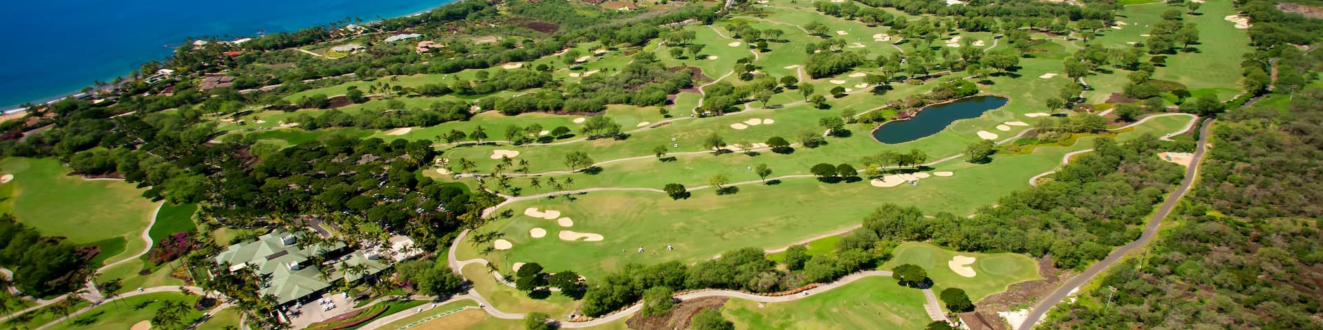 A golf course with a view of the ocean and a mountain in the distance.