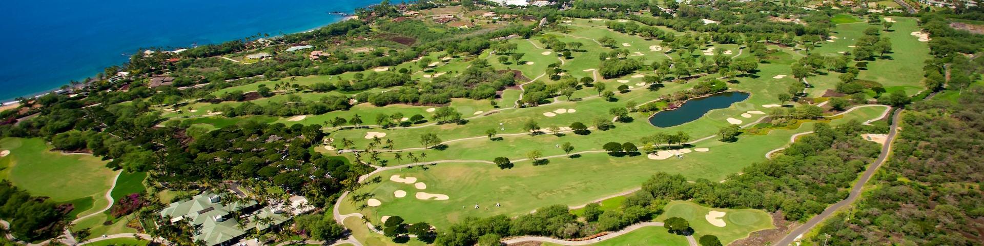 Un campo de golf con vista al océano y una montaña a lo lejos.