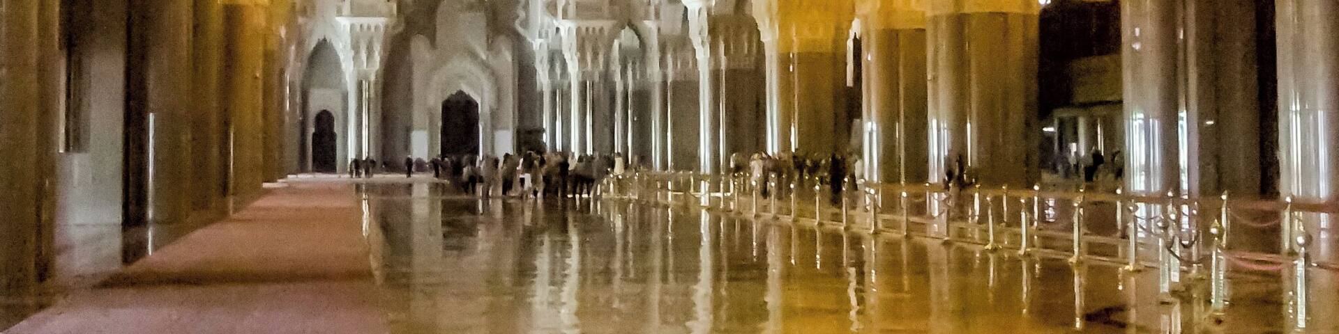 A grand hall with high ceilings, ornate columns, and a reflective floor.