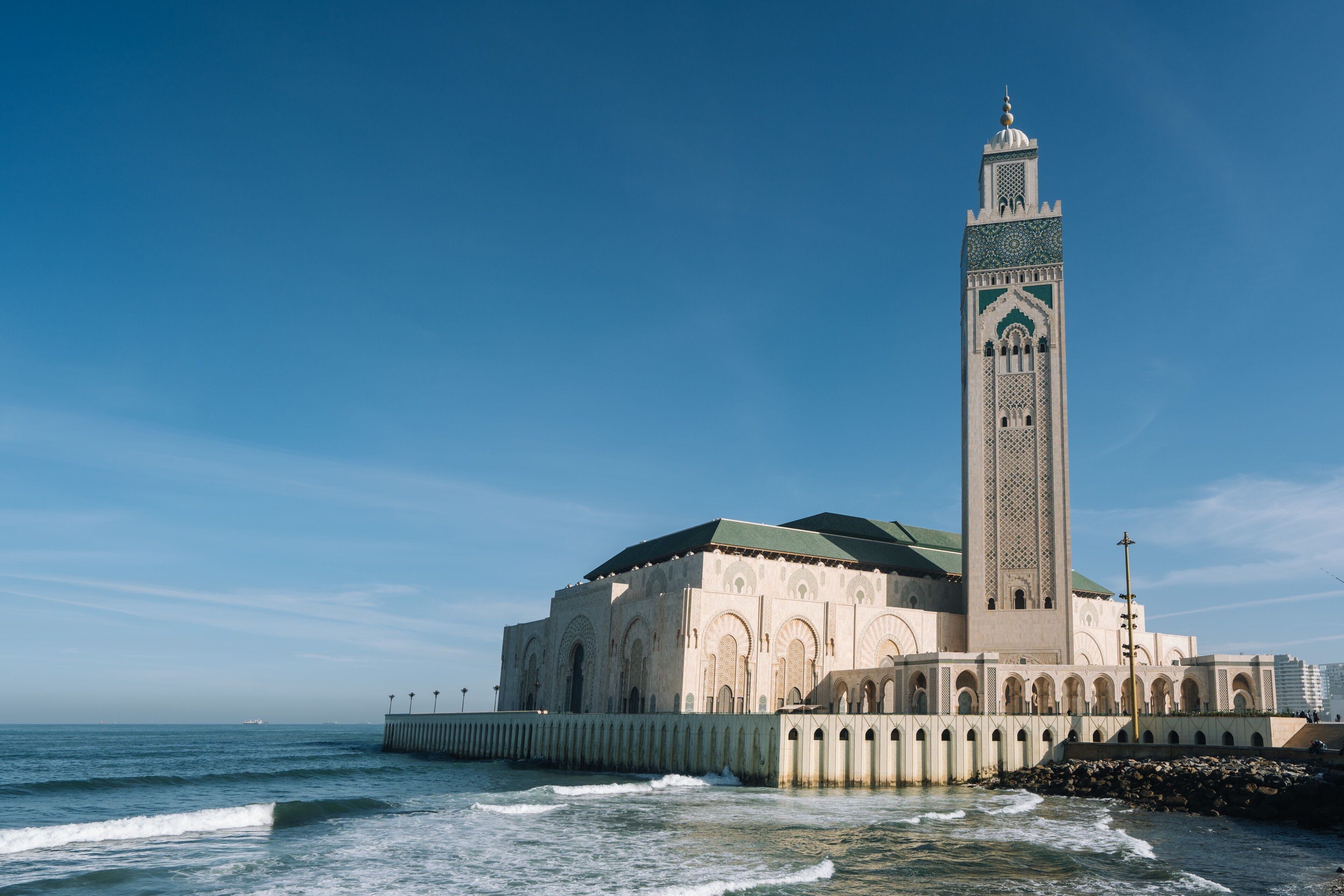 Una gran mezquita con un alto minarete frente al mar.